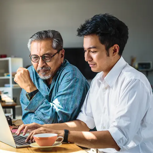 photo of father and son using laptop