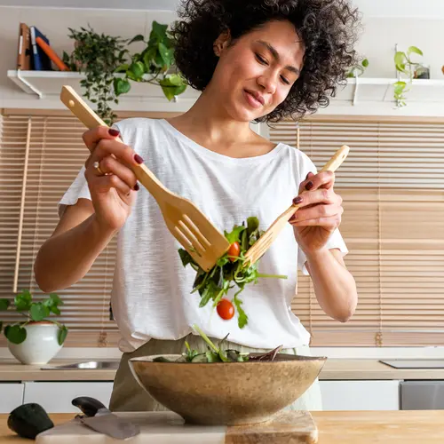 photo of young woman making fresh salad